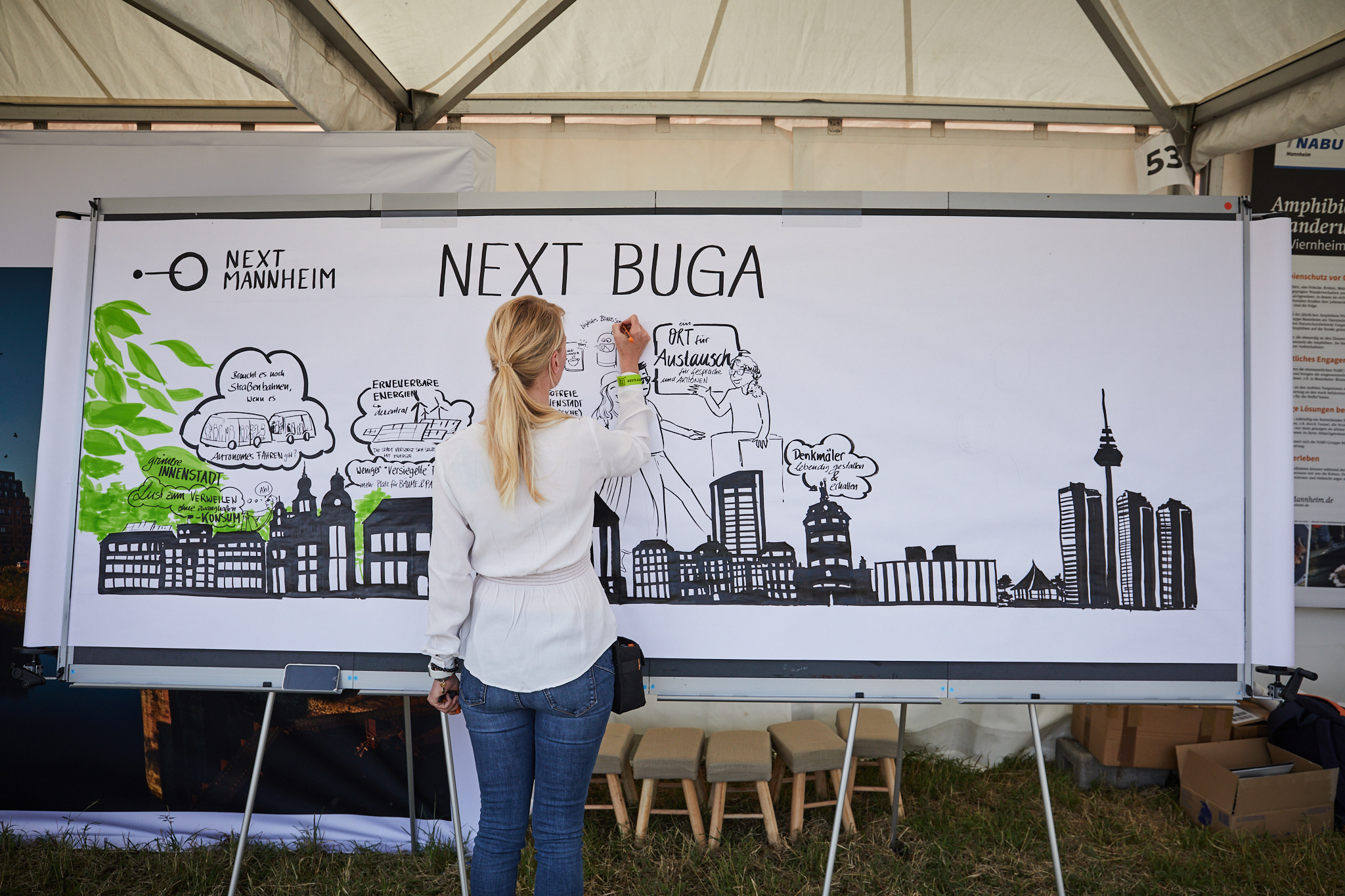 Eine Frau zeichnet auf ein Whiteboard mit der Skyline von Mannheim