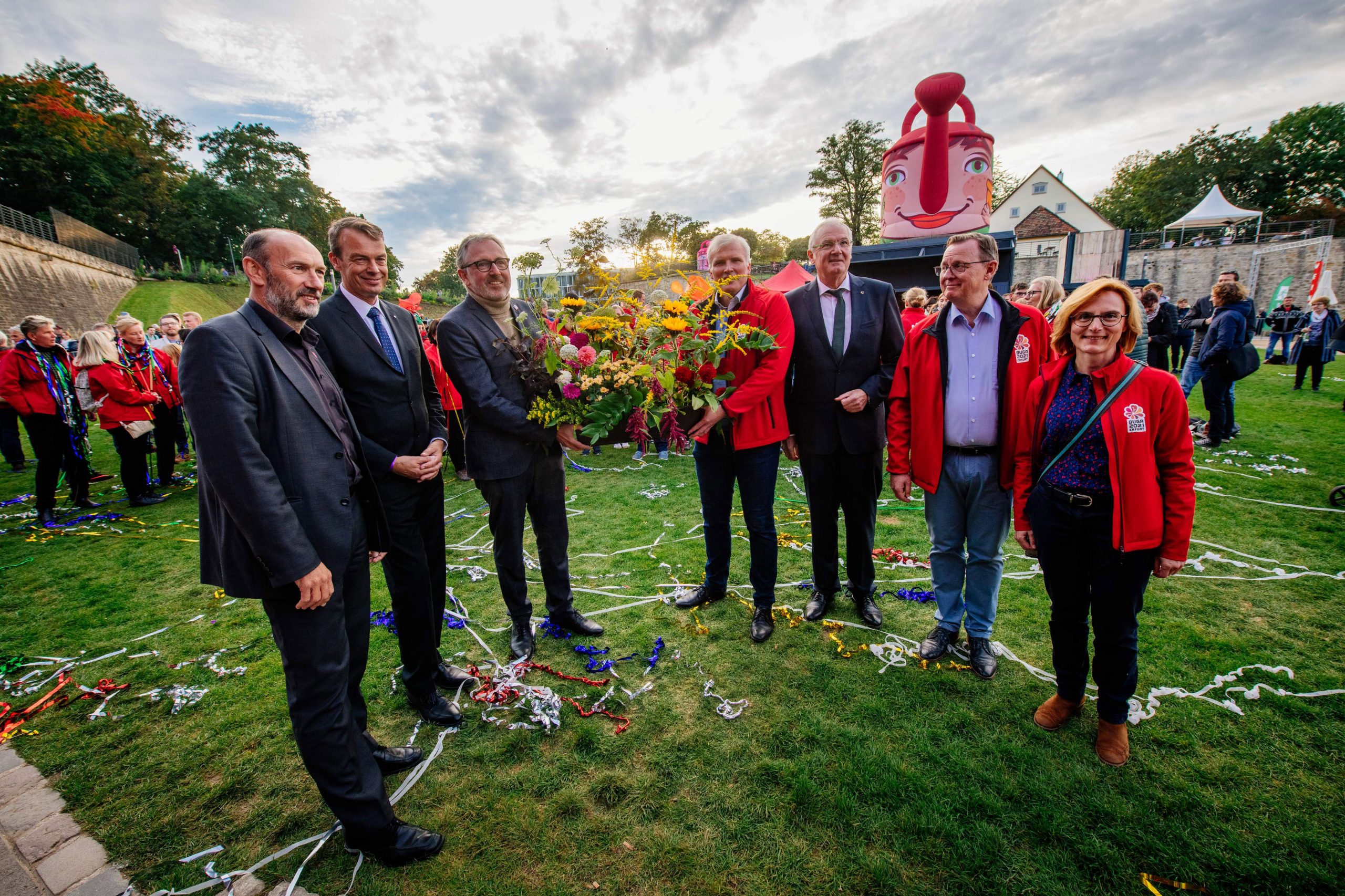 Sieben Menschen, darunter Oberbürgermeister Dr. Peter Kurz und BUGA 23 Geschäftsführer Michael Schnellbach stehen in einem Halbkreis und halten einen Blumenstrauß