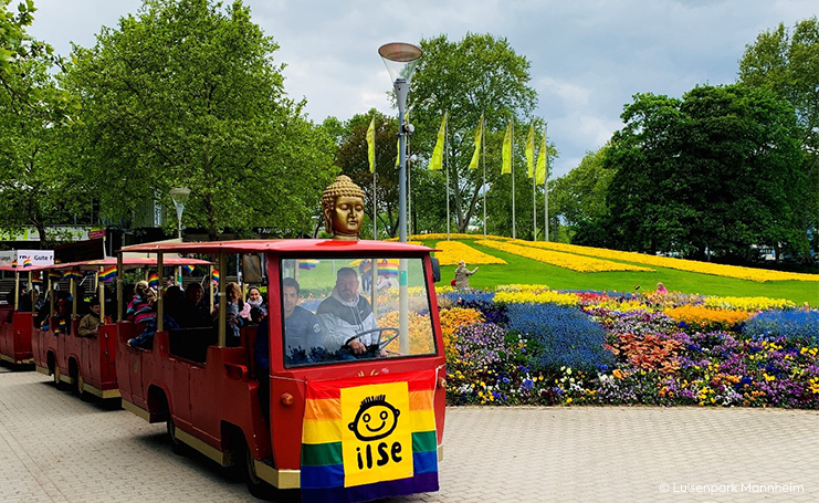 Eine kleine Bahn fährt im Luisenpark. Blumenbeete im Hintergrund