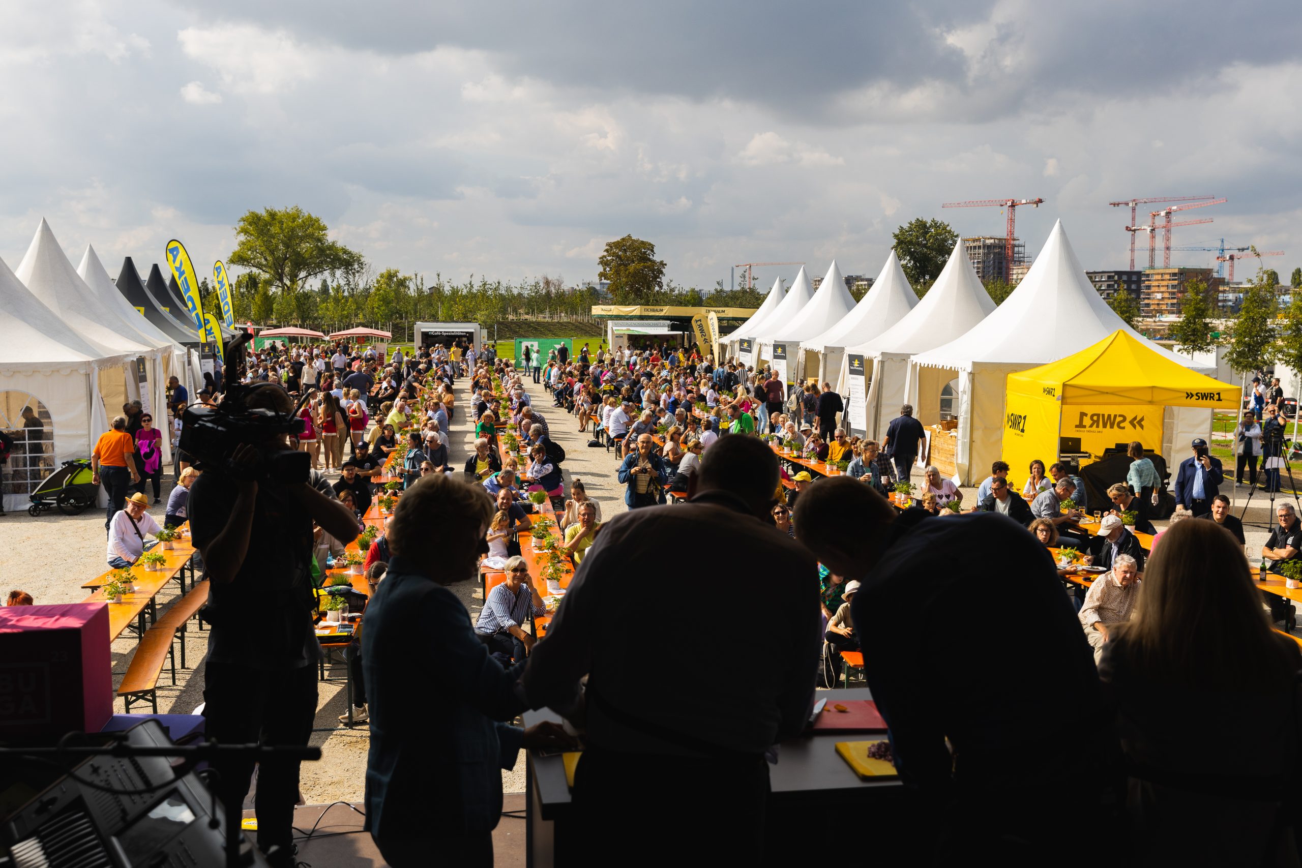 Ein Blick von der Bühne des SWR 1 Pfännle, Biergarnituren mit essenden Menschen werden seitlich von weißen Zelten flankiert