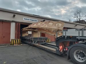 Ein LKW mit Holzgerüst auf der Ladefläche fährt rückwärts in eine Lagerhalle