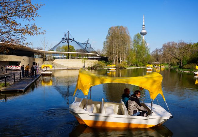 Die bekannten Gelb-Weißen Gondolettas des Luißenparks fahren auf dem Kutzerweiher. Im Hintergrund der Fernmeldeturm