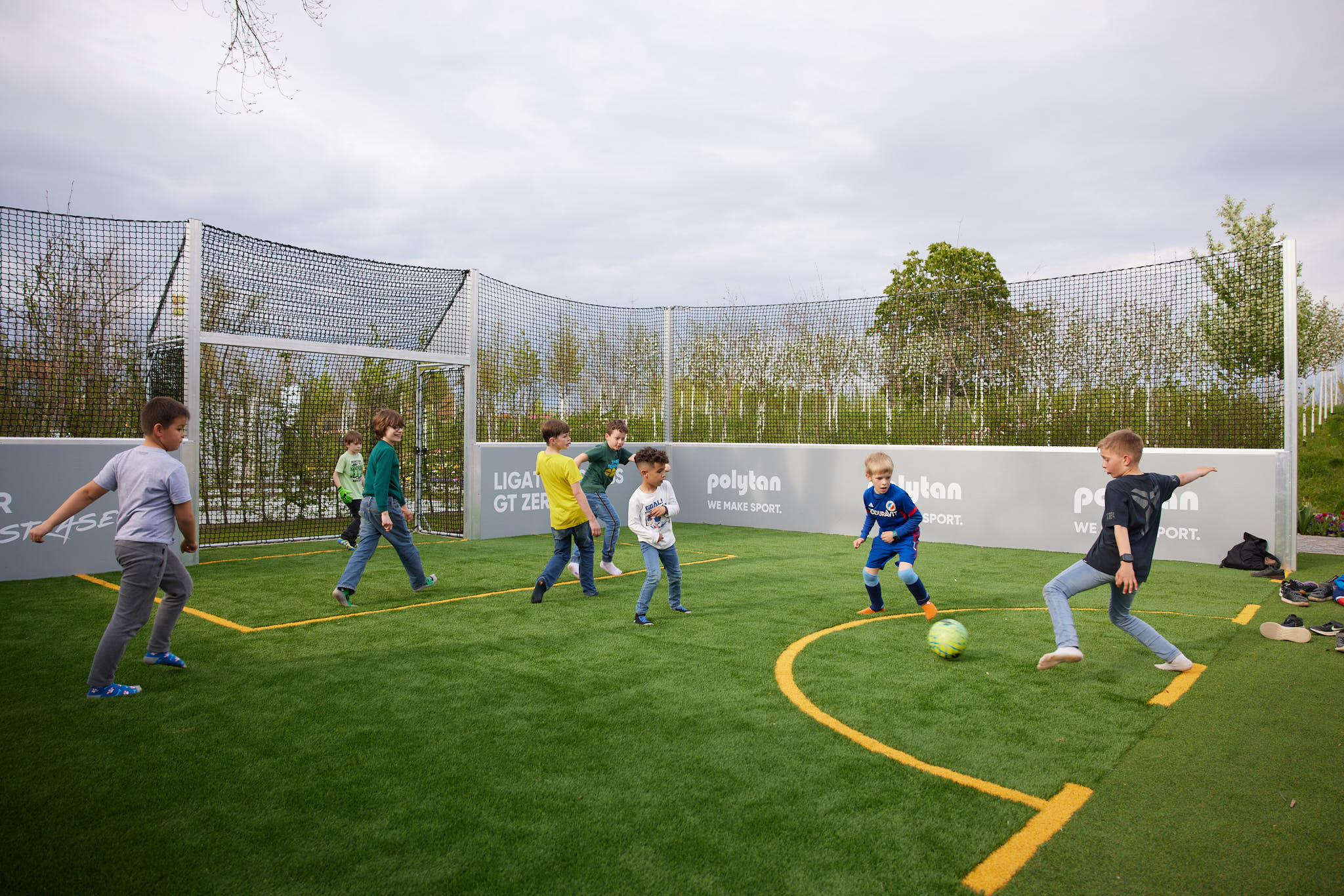 Kinder spielen Fußball in einem eingezäunten Spielfeld