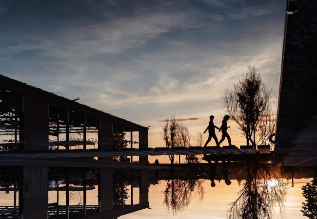Menschen laufen bei Sonnenuntergang über den Wasserspiegel im Innenhof der U-Halle
